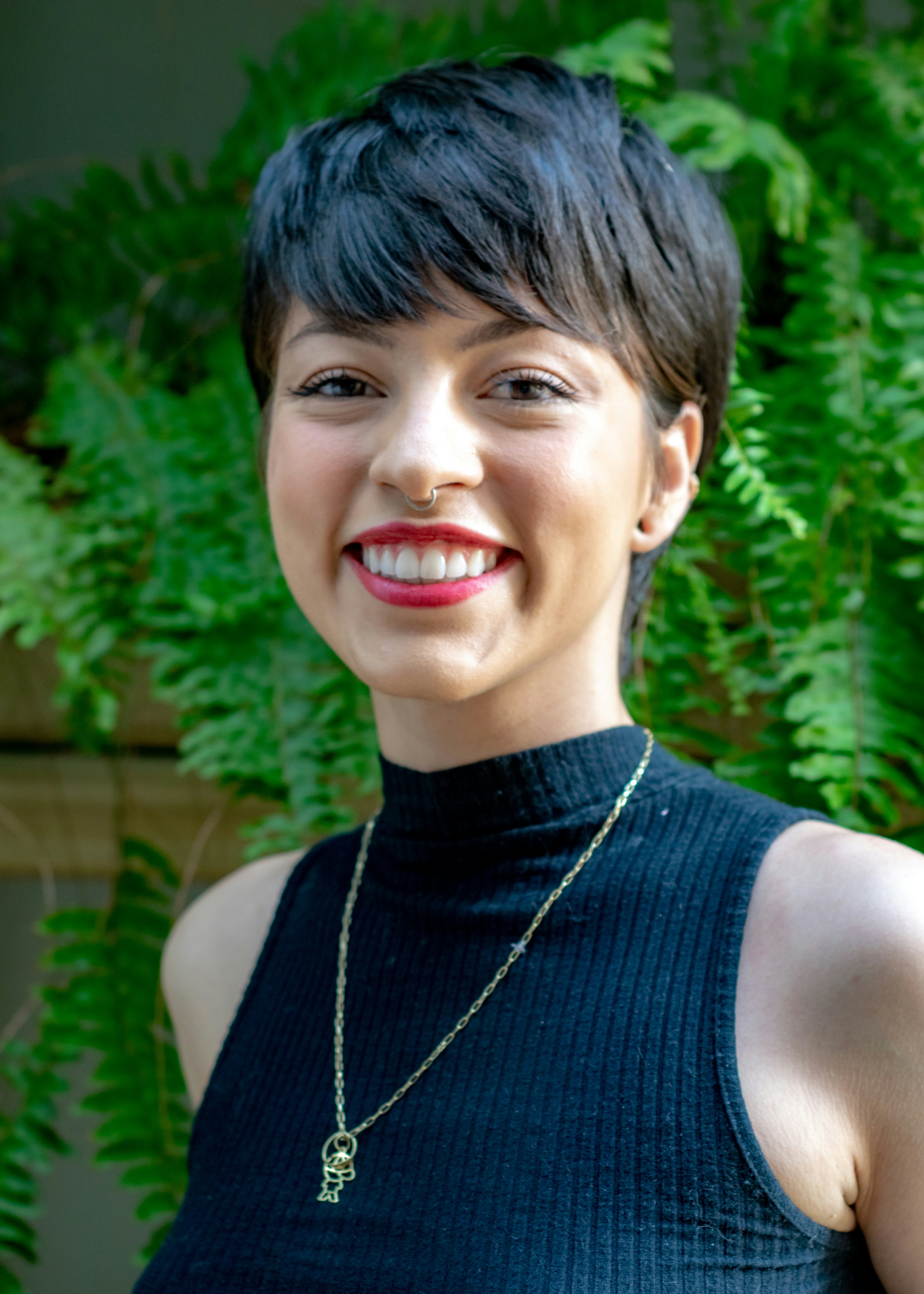 smiling woman in sleeveless turtleneck top with gold necklace